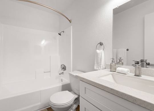 A white bathroom with a toilet, sink, and bathtub.