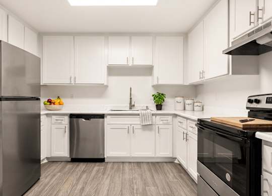 A modern kitchen with white cabinets and stainless steel appliances.