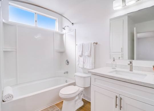 A white bathroom with a toilet, sink, and bathtub.