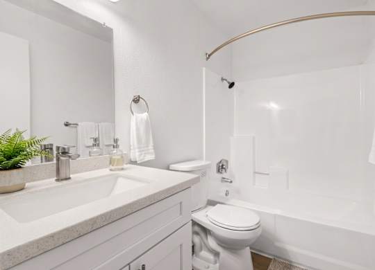 A white bathroom with a toilet, sink, and bathtub.