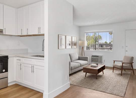 A modern kitchen with white cabinets and a grey sofa.