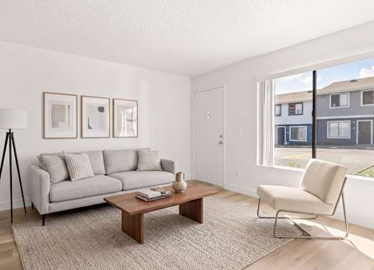 A living room with a grey couch, a coffee table, and a chair.