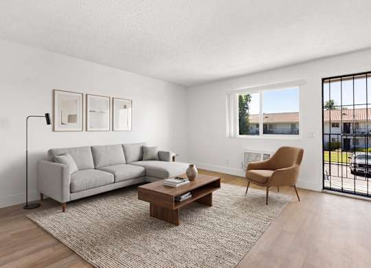 A living room with a grey couch, a brown armchair, a coffee table, and pictures on the wall.