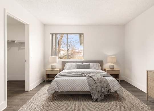 A bedroom with a bed, nightstands, and a window.