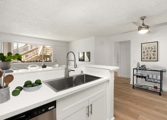 A kitchen with white cabinets and a stainless steel sink.