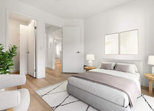 A bedroom with a large bed, a chair, and a potted plant.