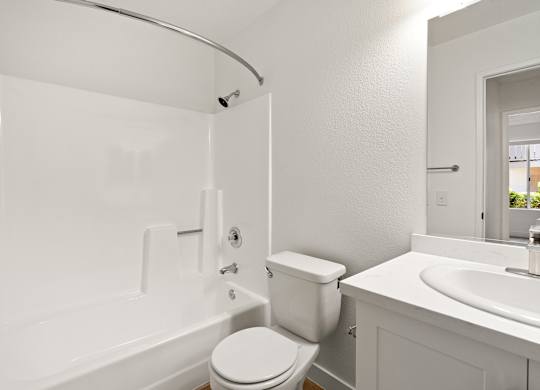 A white bathroom with a toilet, sink, and bathtub.