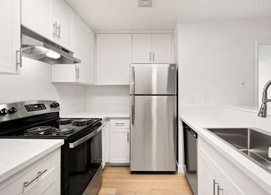 A modern kitchen with a stainless steel refrigerator and black countertops.
