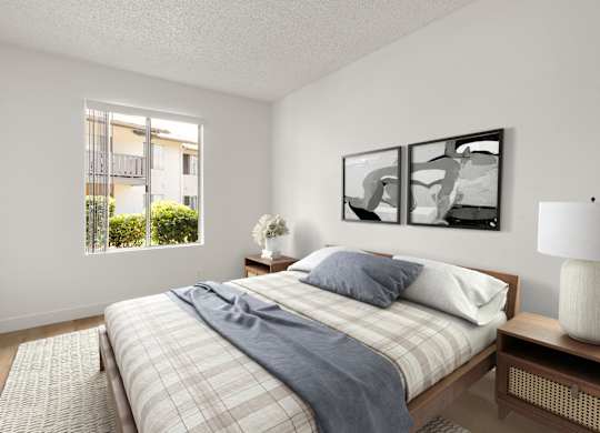A bedroom with a bed, nightstand, and a window with a view of a building outside.