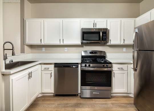 A kitchen with a stainless steel refrigerator, oven, and microwave.