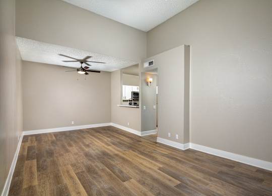 A room with a ceiling fan and wooden flooring.