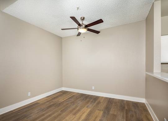 A room with a ceiling fan and wooden flooring.