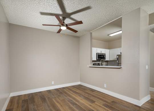A room with a ceiling fan and wooden flooring.