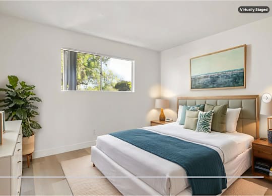 A bedroom with a large bed and a painting on the wall.