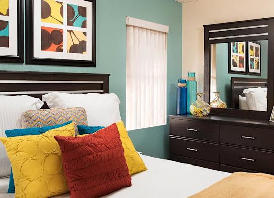 A bedroom with a bed, dresser, and mirror.