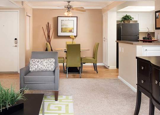 A living room with a grey couch, a green chair, a coffee table, and a flat screen TV.