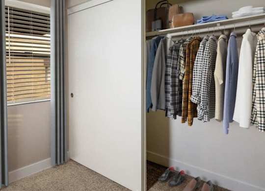 A closet with clothes and shoes.