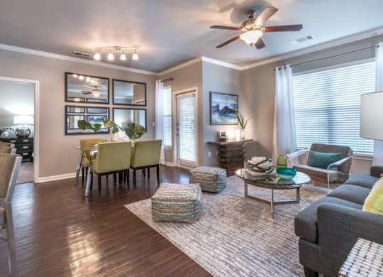 A well-lit living room with a dining area and a ceiling fan.