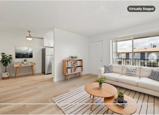 A modern living room with a white sofa, a wooden coffee table, and a large window.
