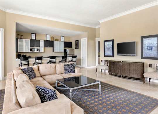 A living room with a tan couch and a glass coffee table.