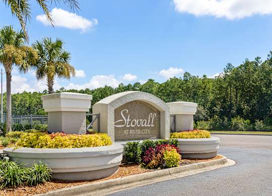 A sign that says Stovall at River City surrounded by plants and trees.
