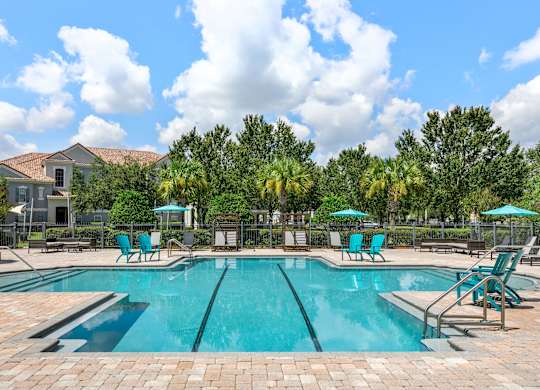 A large swimming pool surrounded by blue lounge chairs and umbrellas.