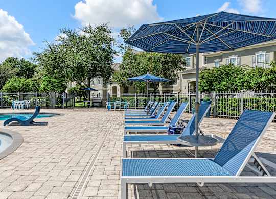 A pool area with sun loungers and a blue umbrella.