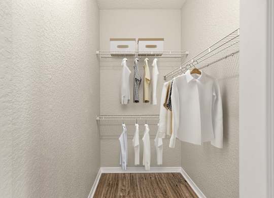 A white closet with clothes hanging on a wire rack.