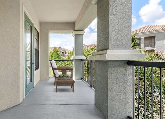 A balcony with a chair and a table with a plant on it.