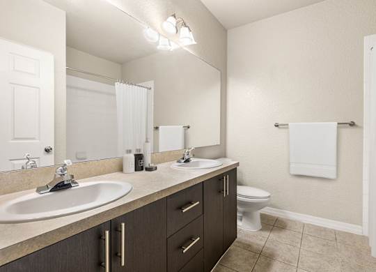 A bathroom with a white sink, toilet, and a mirror.