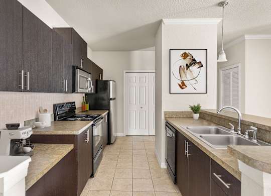 A kitchen with brown cabinets and a black microwave.