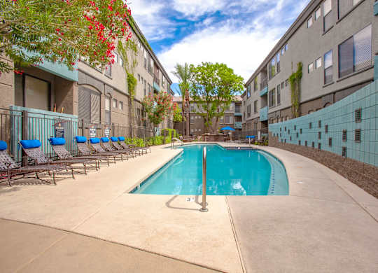 A swimming pool surrounded by a wall and chairs.