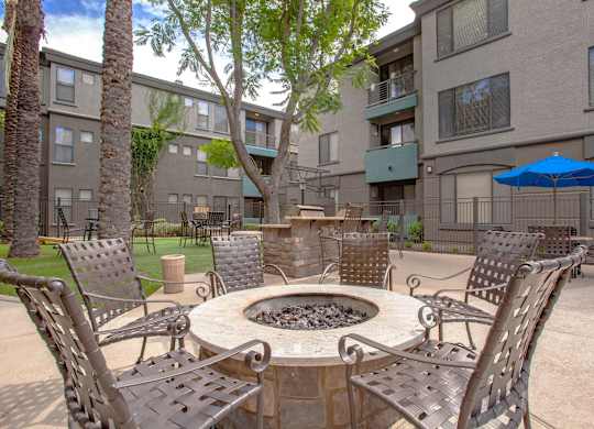 A patio with chairs and a fire pit in front of a building.