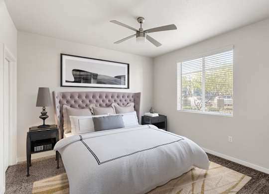 A bedroom with a large bed and a ceiling fan.