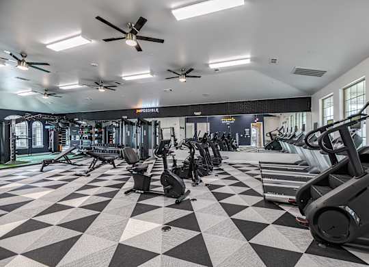 A gym with a variety of equipment including treadmills, stationary bikes, and elliptical machines.