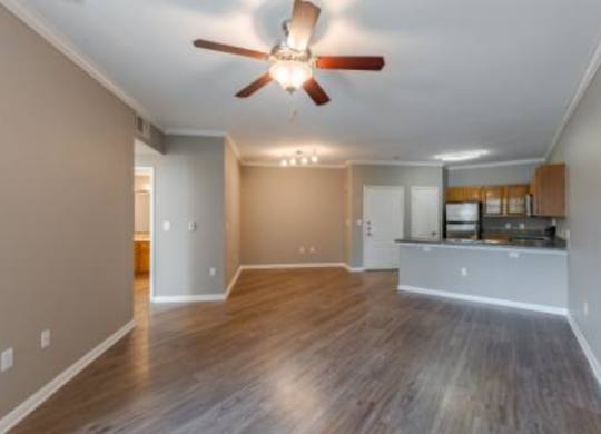 A spacious room with a ceiling fan and hardwood flooring.