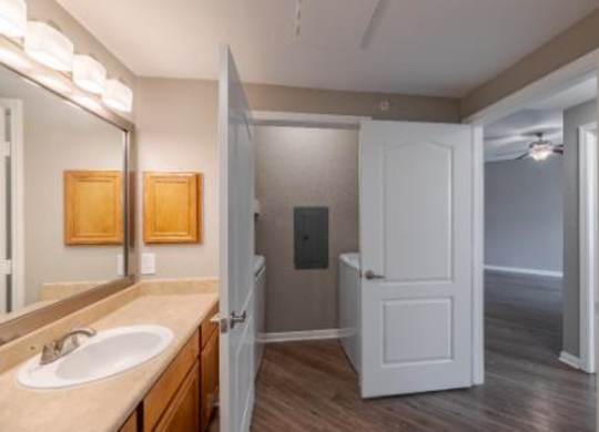 A bathroom with a sink, mirror, and a door.