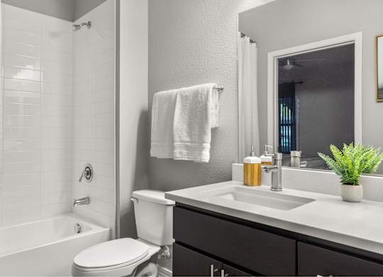 A white towel hangs on a wall above a white sink in a bathroom.