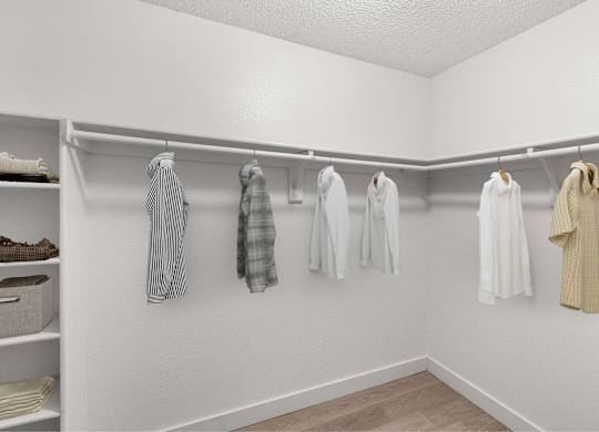 A white closet with clothes hanging on hangers.