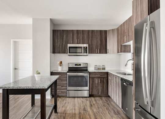 A modern kitchen with a granite table and stainless steel appliances.