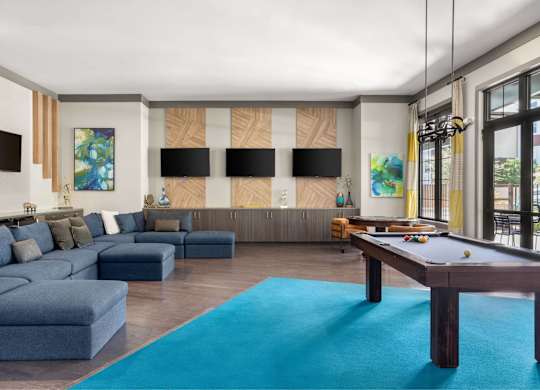 A living room with a pool table and a blue rug.