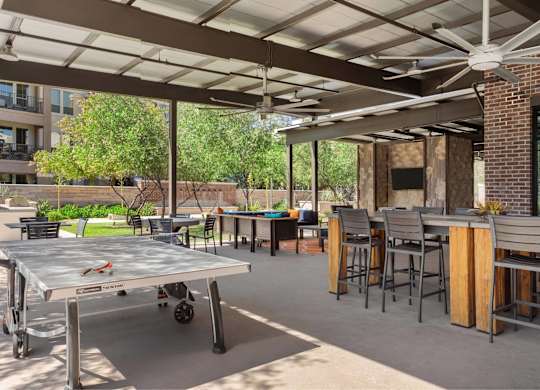 A patio with a table and chairs under a roof.