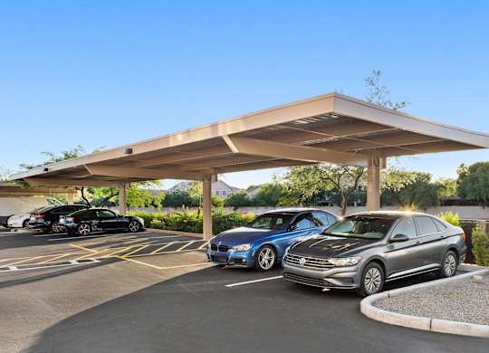 A parking lot with cars parked under a shelter.