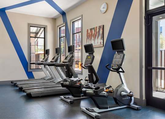 A gym with treadmills and a clock on the wall.
