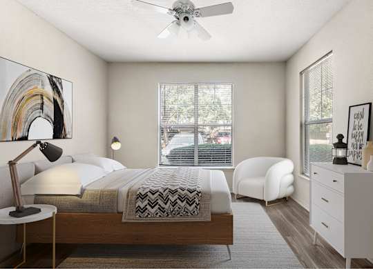 A bedroom with a bed, chair, and a ceiling fan.