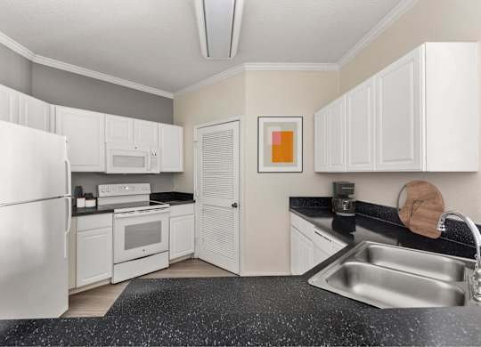A kitchen with white cabinets and a black countertop.