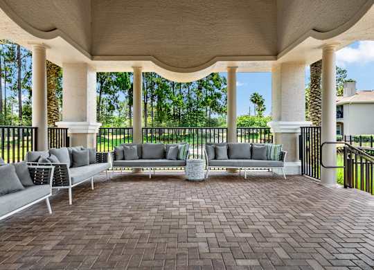 A patio with a white couch and a table with a vase on it.