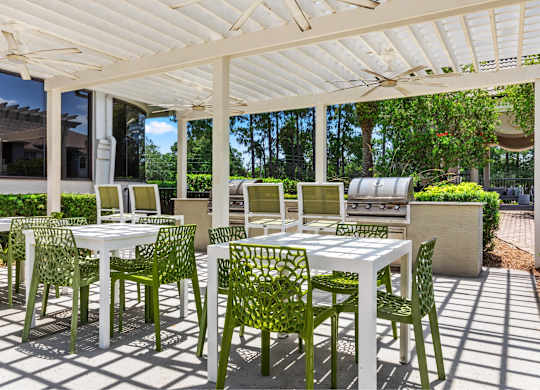 A white table and green chairs are set up under a white canopy.