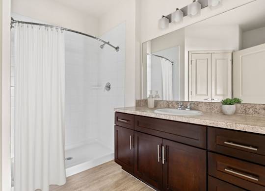 A bathroom with a white shower curtain and a brown vanity.