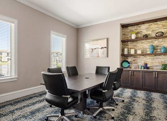 A conference room with a stone wall and a table with four chairs.